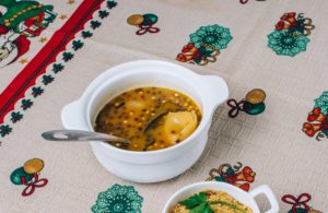 molho de frutas amarelas em um pote branco sobre uma mesa com toalha natalina